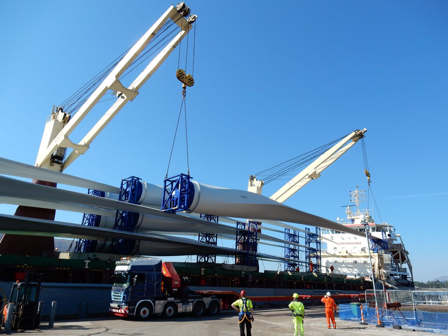 Wind turbine blades being loaded onto a vessel from a dock