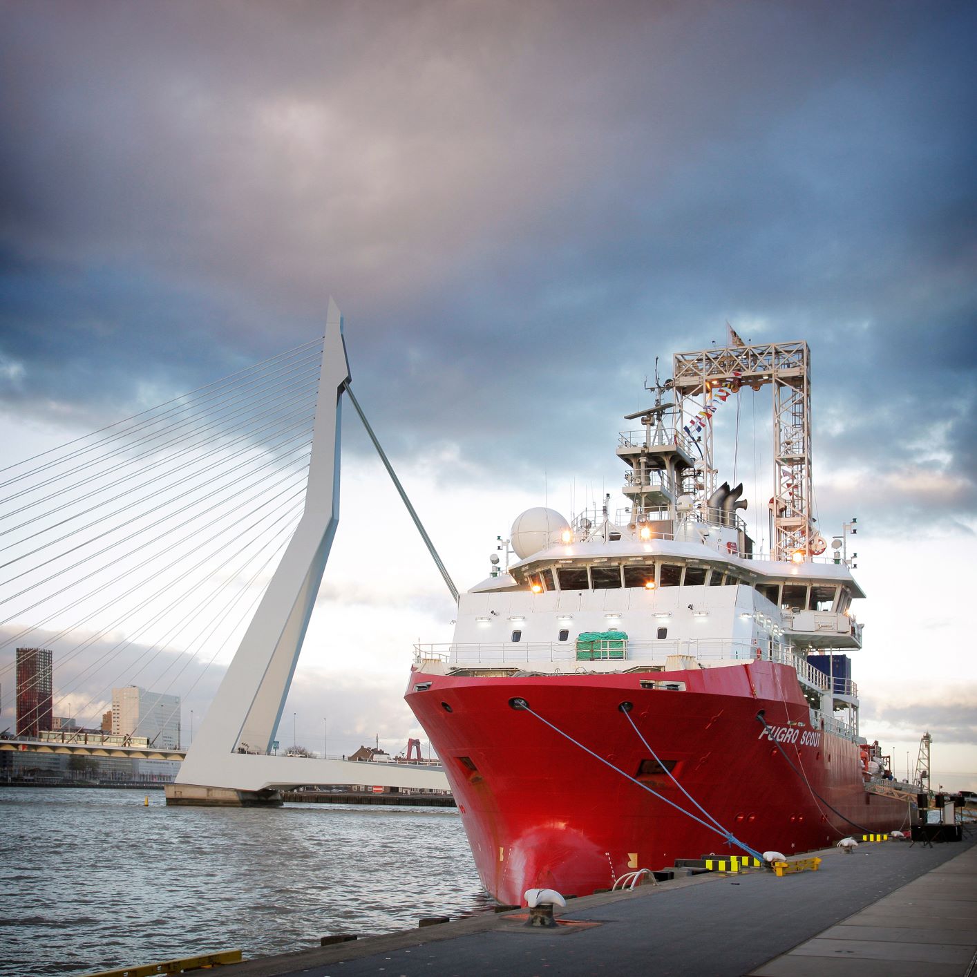 The Fugro Scout vessel photographed from the dock in Rotterdam, showing vessel's bow close up and Rotterdam bridge in the back