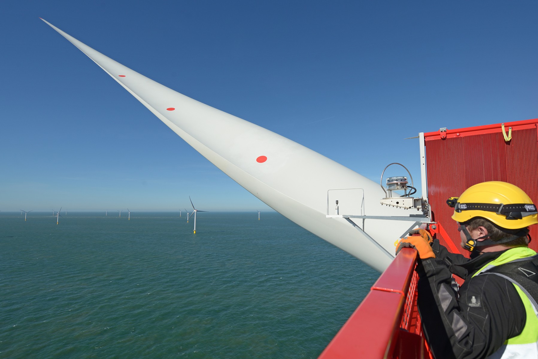 An offshore wind technician on top of a wind turbine