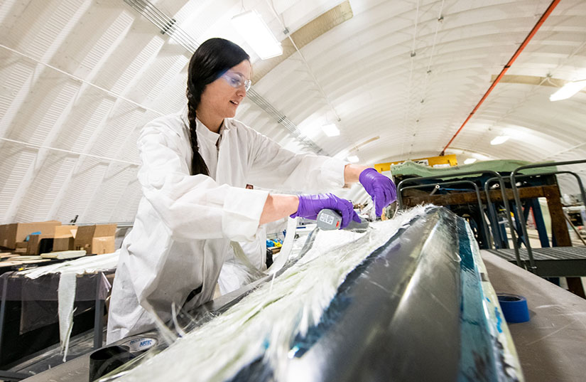 NREL researcher working on a thermoplastic composite turbine blade at the Composites Manufacturing Education and Technology Facility at NREL's Flatirons Campus.