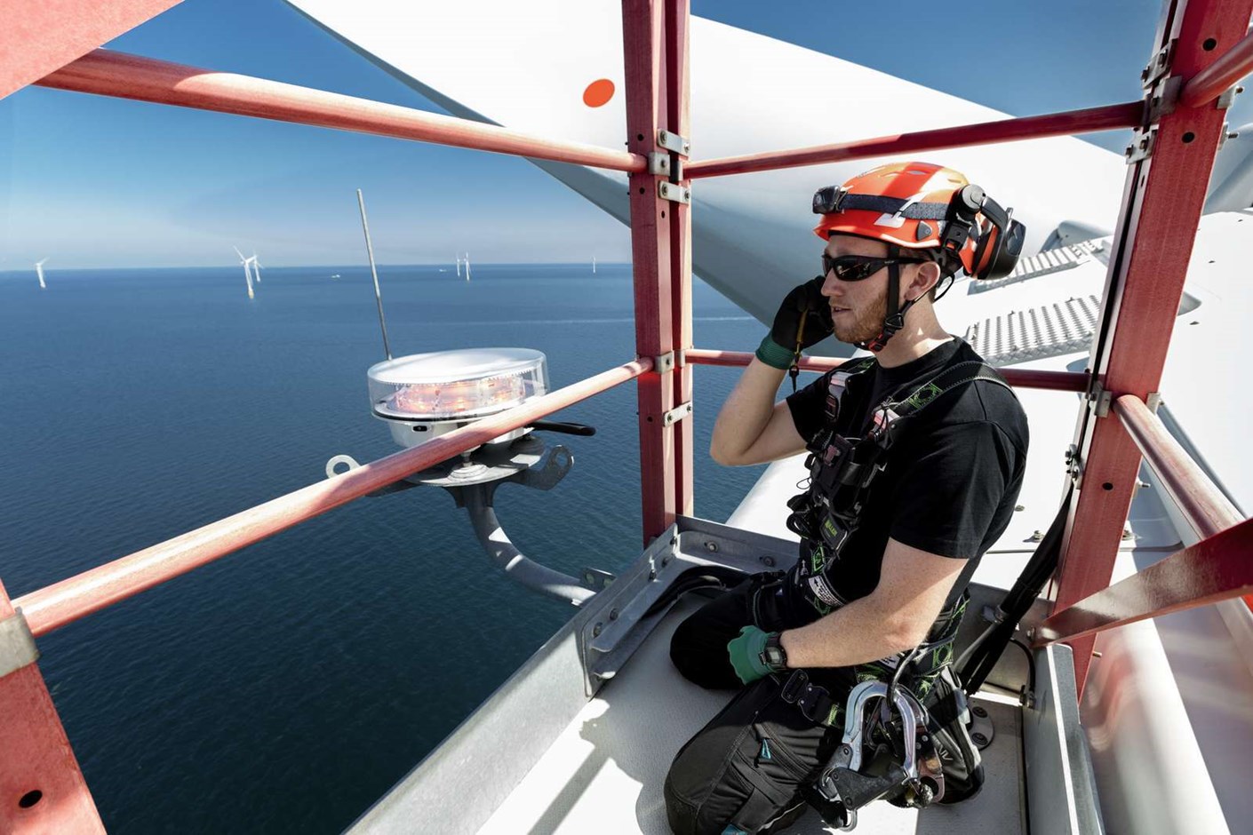A wind turbine technician on top of an offshore wind turbine
