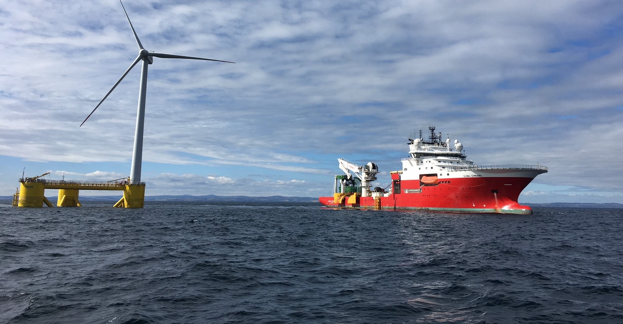 A vessel next to a floating wind turbine