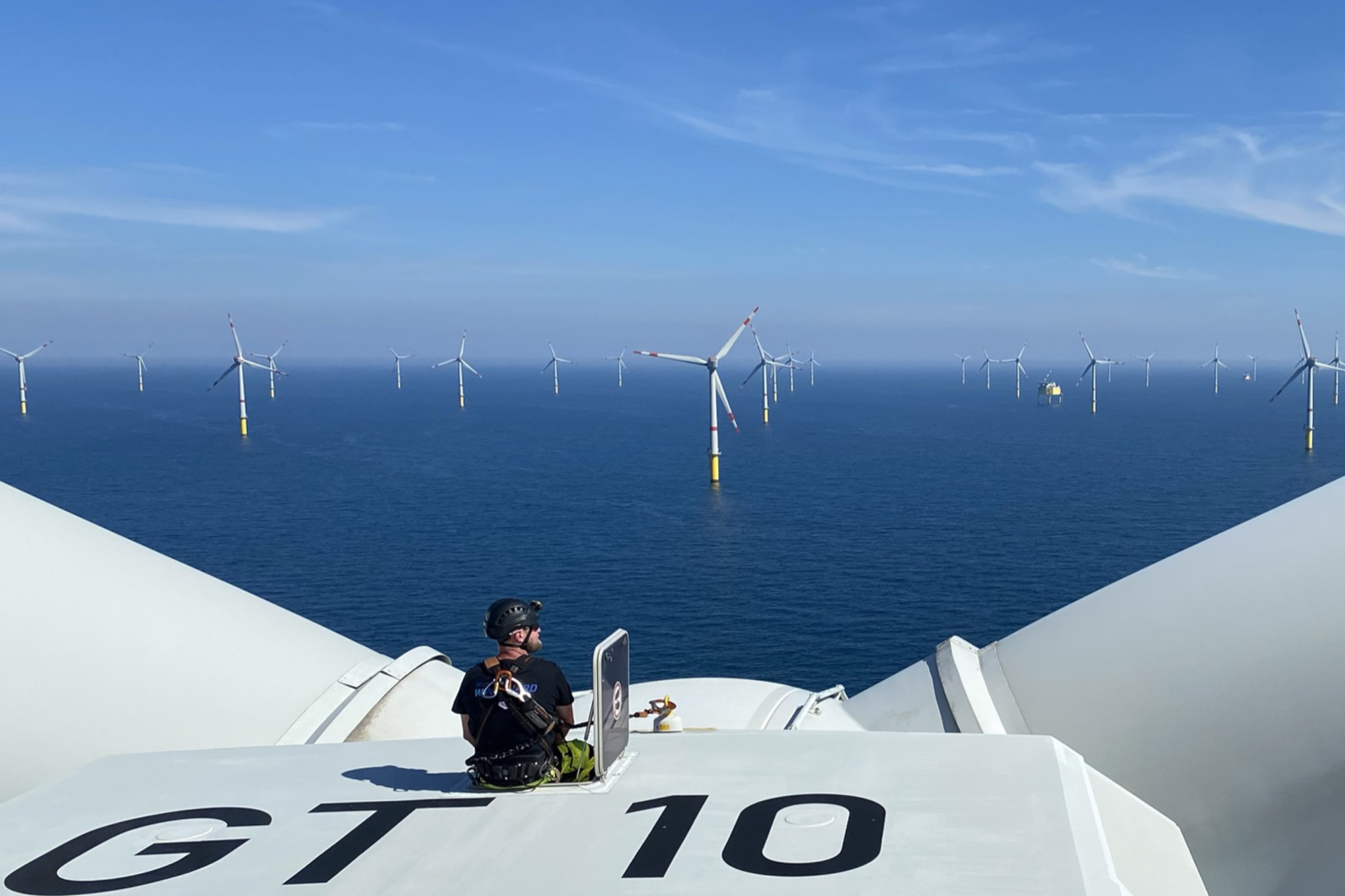 A photo of a Deutsche WindGuard inspector on top of an offshore wind tutbine at Global Tech 1 offshore wind farm