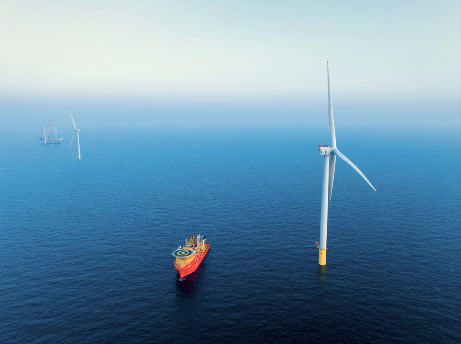 An aerial photo of wind turbines and a red vessel at Dogger Bank Wind Farm