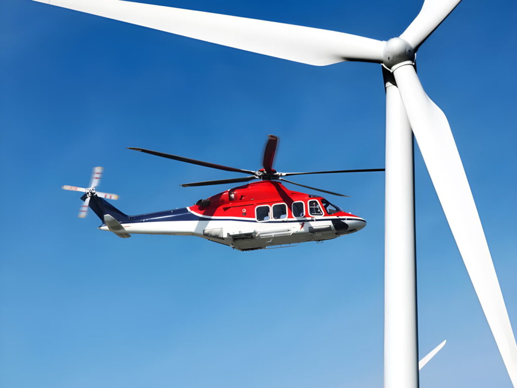 A photo of CHC's Leonardo AW139 helicopter in flight next to a wind turbine