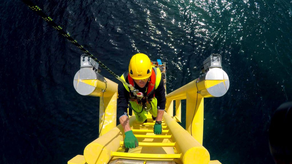 Offshore wind worker climbing a transition piece.