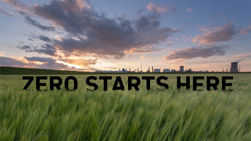 An image from The Zero Carbon Humber (ZCH) Partnership with "zero starts here" positioned in the grass with a city in the background