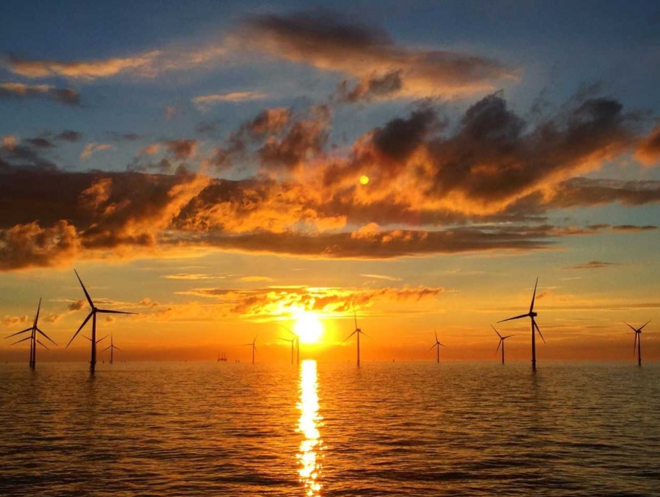 A photo of an offshore wind farm in sunset