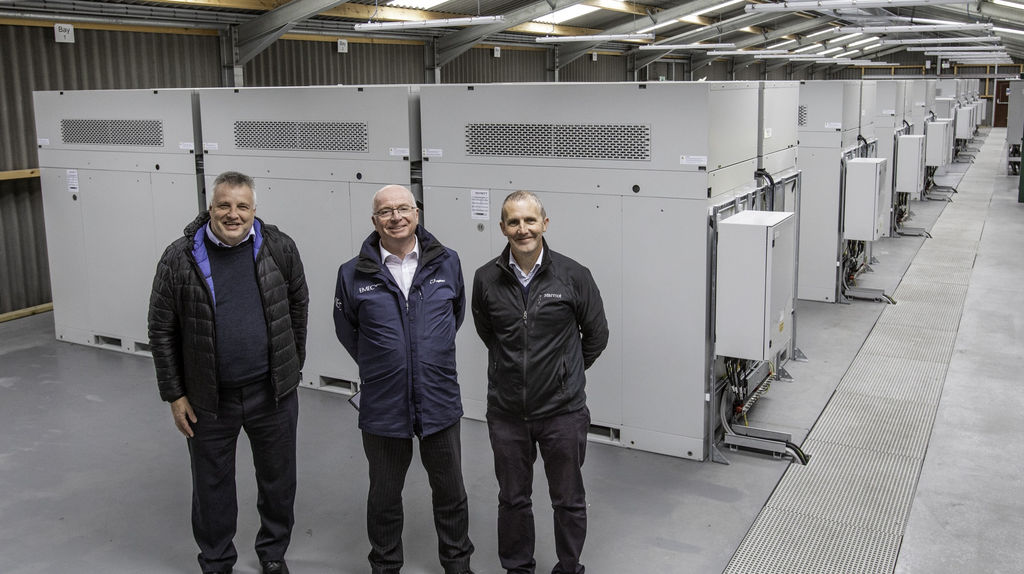 Graeme Harrison, HIE; Neil Kermode, EMEC; and Michael Matheson MSP in front of 48 Invinity VS3 modules on site (Courtesy of Invinity Energy Systems/Photo by Colin Keldie)