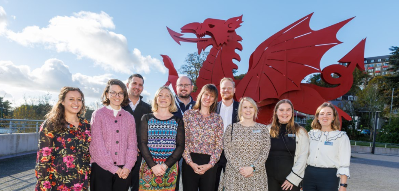 group of workers from RenewableUK Cymru standing in front of a red dragon statue