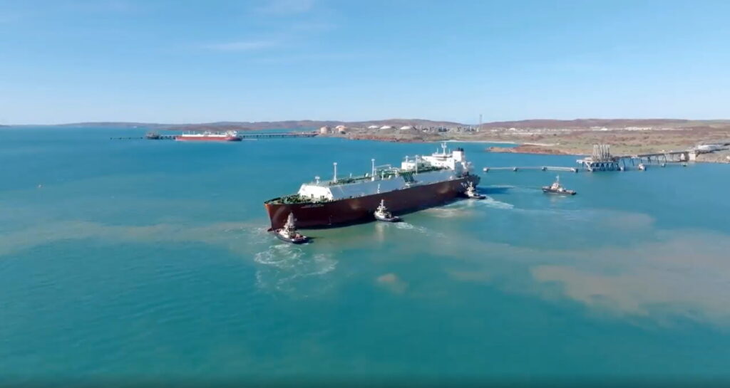 LNG vessel surrounded by four tugboats approaching a jetty