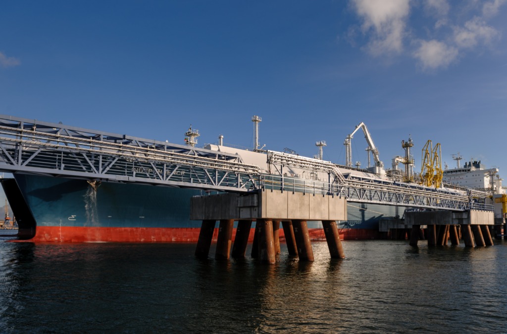 A view of some pipes in the foreground and a vessel in the background