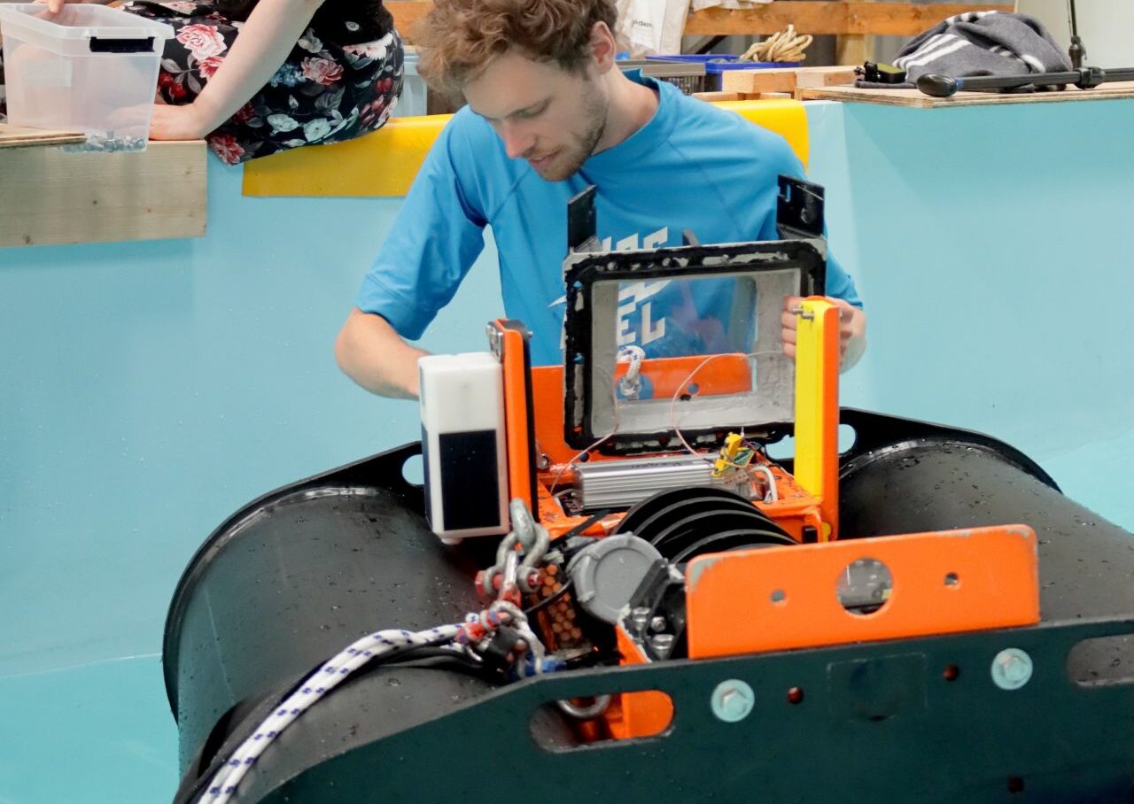 A man in blue shirt working on a wave energy converter