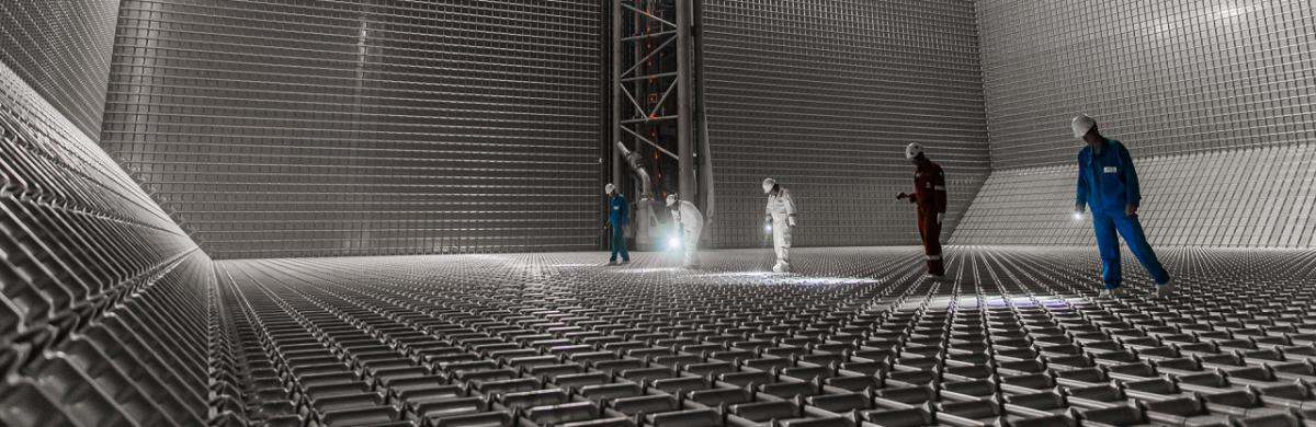 Four persons with flashlights inspecting the interior of a metal construction