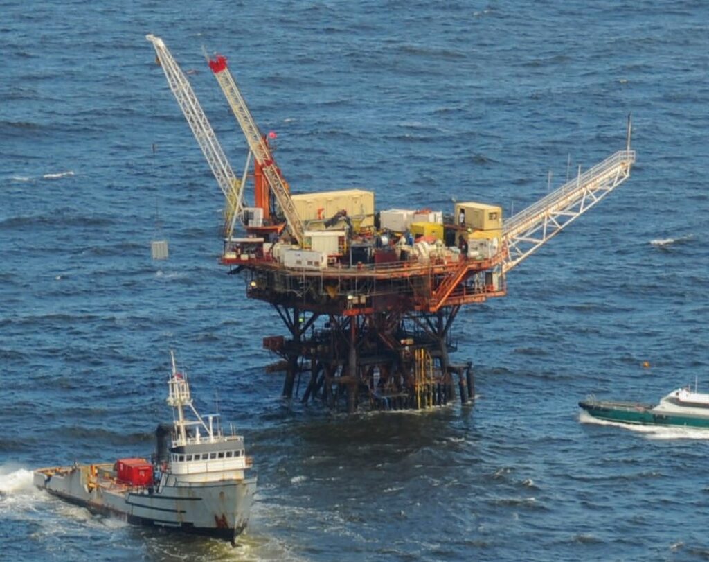 An offshore platform with cranes surrounded by two vessels