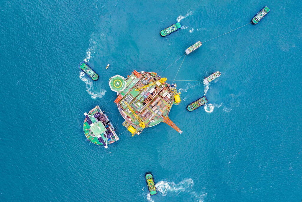 An aerial view of a circular offshore platform surrounded by several smaller vessels