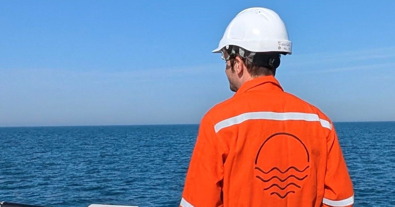 A worker in orange uniform and white head protection from Ocean Geophysics