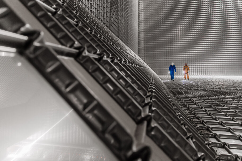 Two men inside a room with all surfaces covered in metal