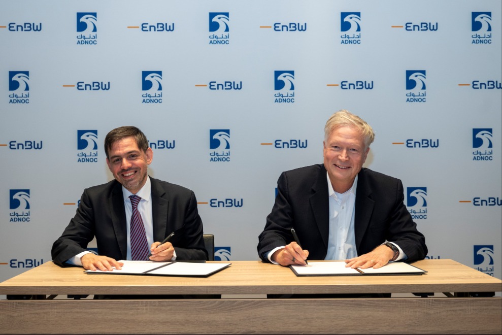 Two men sitting behind a desk signing documents