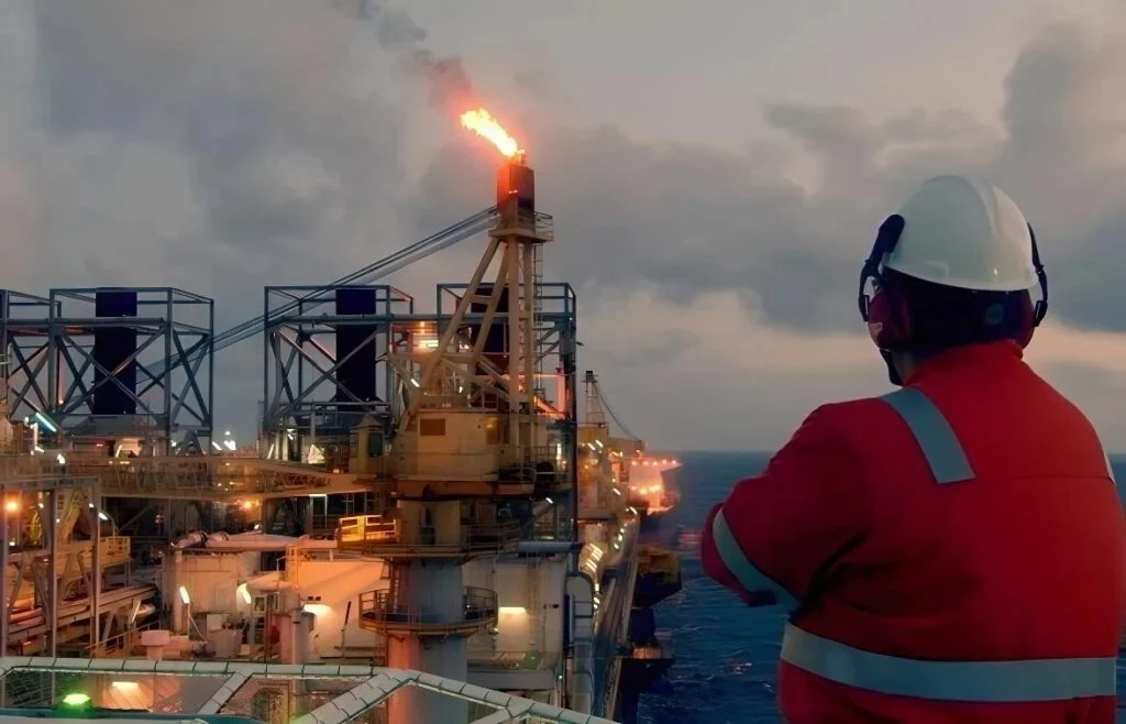 A man viewed from the back looking at an offshore platform