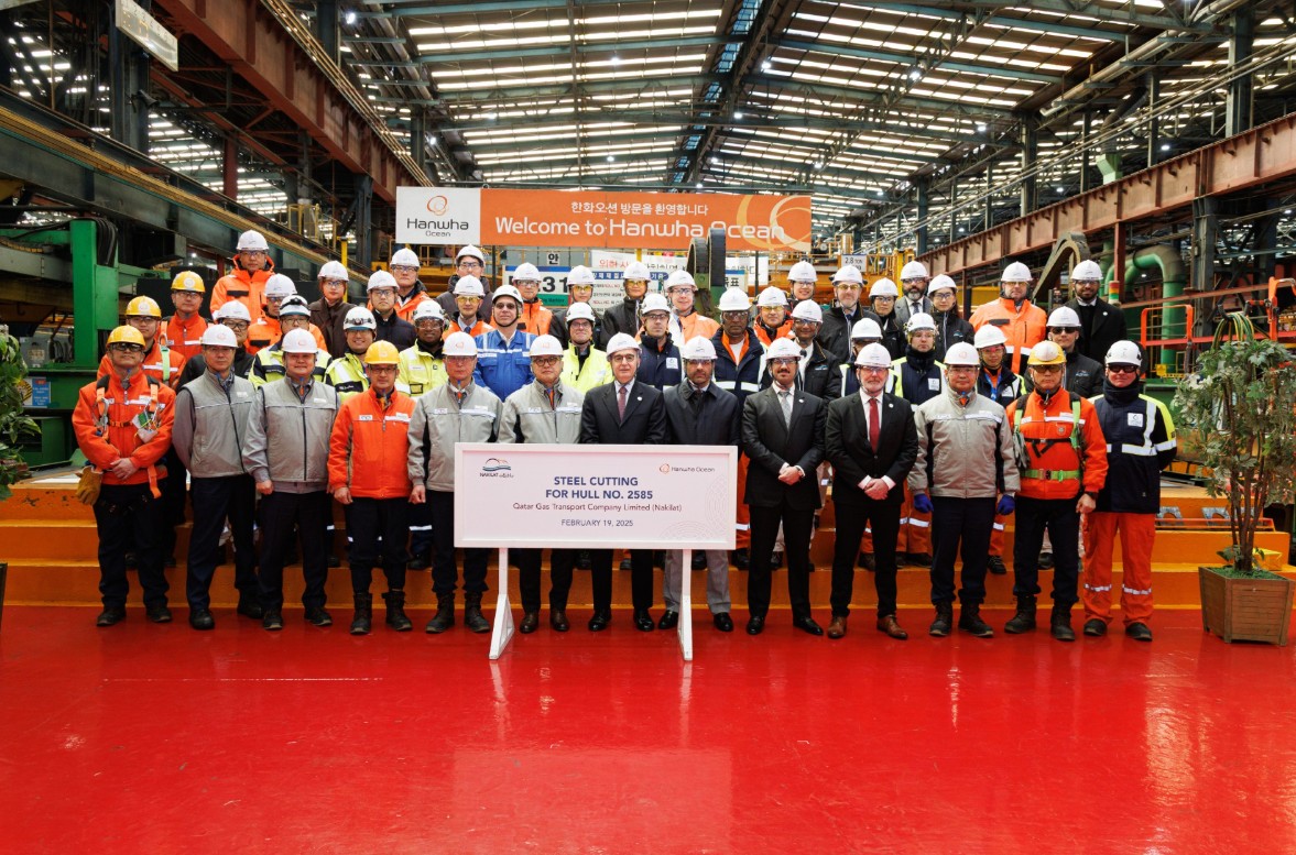 Dozens of people standing in several rows at a steel-cutting ceremony