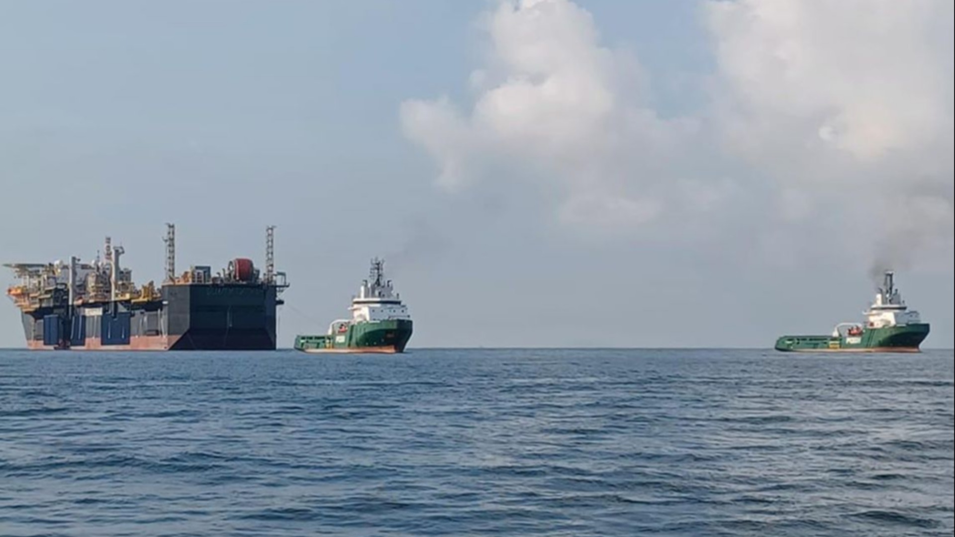A large vessel being towed by two smaller ones