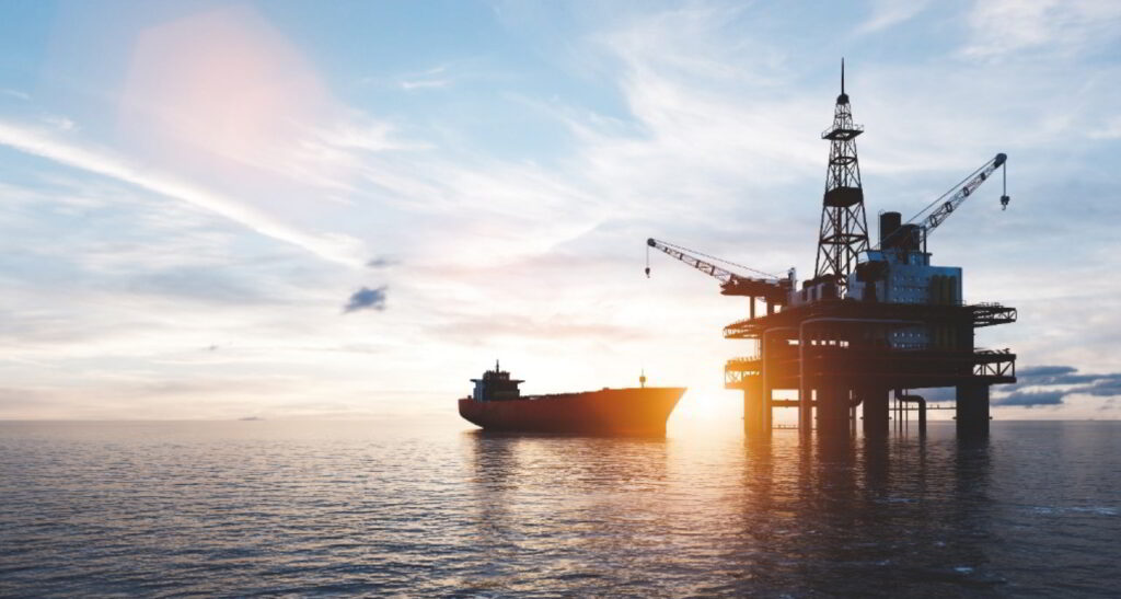 An offshore platform and a vessel next to it at sunset