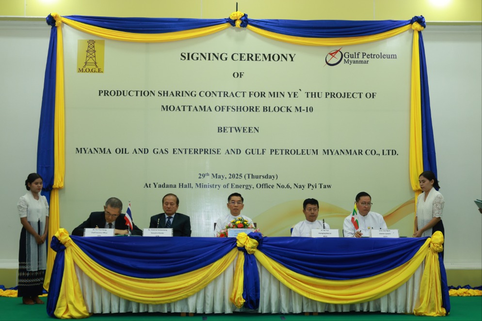 Several men sitting behind a desk at a contract signing ceremony