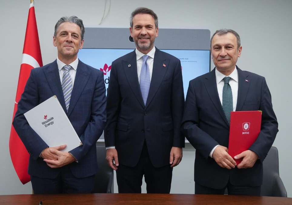 Three men standing at an LNG supply deal signing ceremony